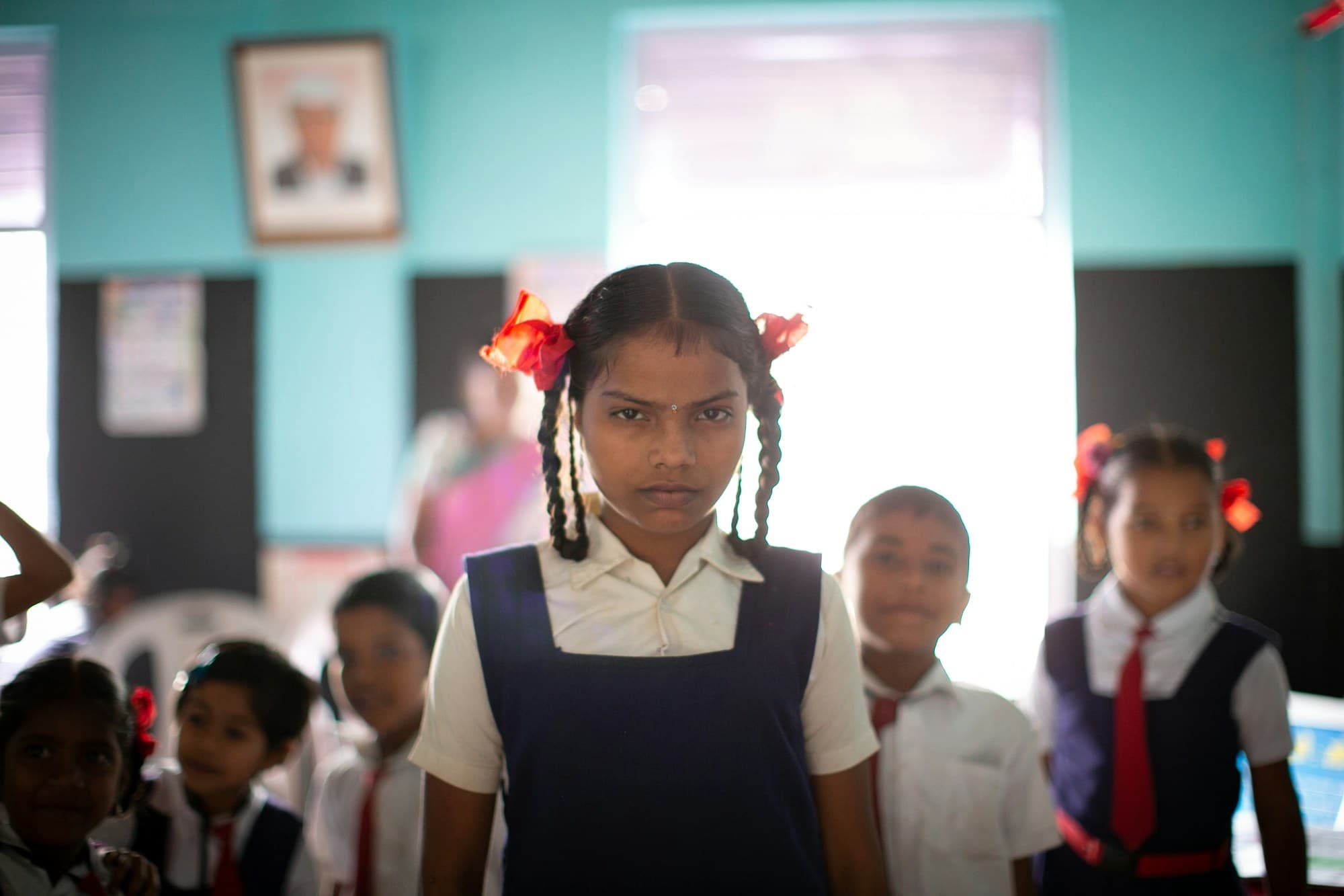 Schoolgirl in uniform with classmates in an Indian classroom